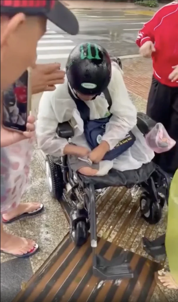 "Volunteers emotionally refuse cash from Chú Dũng while helping unload instant noodles and milk from his wheelchair"