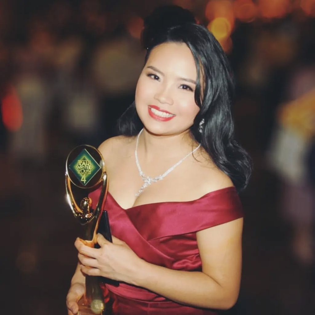 Thai baker Saenglert Ponprapa smiling proudly while holding her Gold Medal certificate and trophy next to her winning masterpiece at the CAKE & BAKE exhibition in Dortmund.