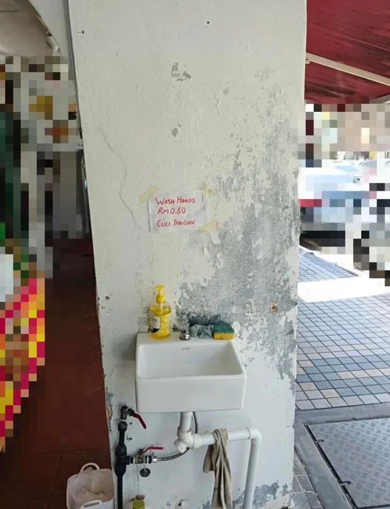 "A handwritten notice taped next to a sink in a Malaysian restaurant stating “Cuci tangan 50 sen” which went viral in December 2025"