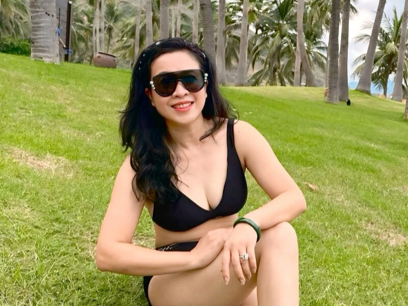 "Thanh Hoa, the elegant wife of Trọng Tấn, looking radiant and youthful in a black bikini during a relaxing beach vacation"