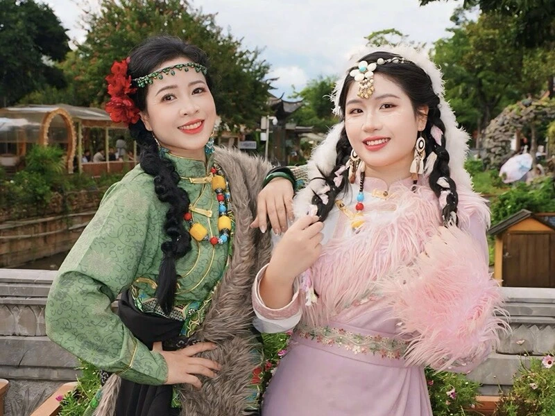Thanh Hoa and her daughter dressed in beautiful traditional Vietnamese costumes, smiling together at a cultural event"