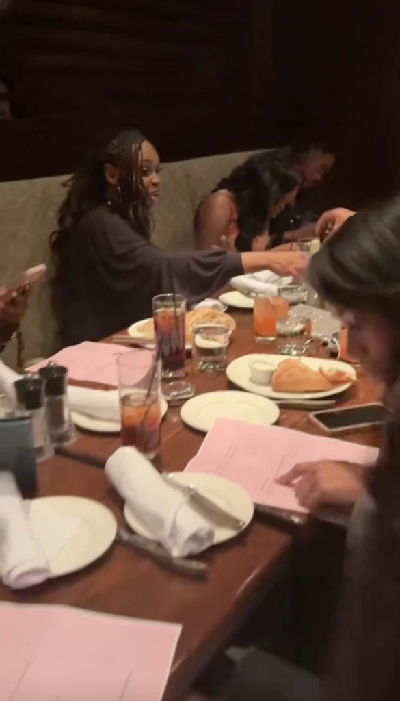 "Nigerian lady distributing maths question papers to friends at birthday dinner party"