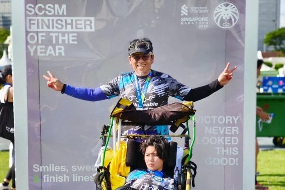 Wira Rabu pushes his daughter, Dihan, in a custom wheelchair during the Singapore half marathon, showcasing their teamwork and determination.