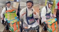 "Mr. Dũng, a disabled elderly lottery ticket seller with no arms and no legs, arrives on his electric wheelchair carrying cartons of instant noodles and milk for flood victims in Đắk Lắk, December 2025"